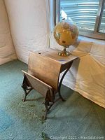 Antique child's school desk with iron base and vintage globe placed on top, showing overall condition and dimensions sticker.