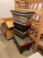 Stacked view of the four Rubbermaid Action Packer storage totes showing the gray and black color scheme with red latches.