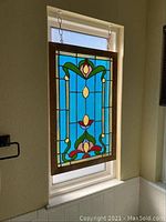 Full front view of stained glass panel showing floral-inspired design and mounting chains.