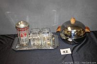 Photo showing the complete cocktail set including ice bucket, tray, four glasses, and shaker on black cloth background.