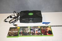 Original Xbox console with cables and four games in cases lined up in front.