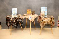 Full lot of three round tables with various scarves, books, and zebra-themed decorative items on top.