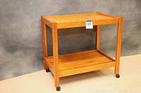 Full side view of wooden tea cart showing the overall structure, two shelves, and caster wheels.