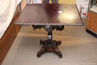 Front angle view of table with both leaves extended showing carved rope edge and pedestal base on casters