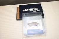 Stamps.com postal scale in original cardboard box and clear plastic packaging on a flat surface
