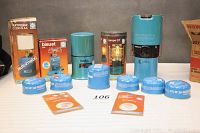 Front view of all items arranged on table, showing boxes for Lumagoz C200 SAA lantern, bluet 206 stove, Lampe GT lamp plus cartridges and mantles.