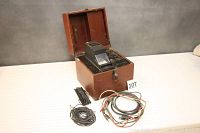 Overall view of the electrocardiograph inside open wooden case, with cables laid out in front.