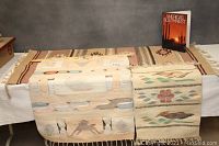 Photo showing all three southwestern-themed tapestries laid out side-by-side on a table with the book 'America's Southwest' upright in the background.