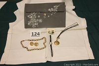 Photo of full lot including gray decorative purse, gold bead clip-on earrings, matching necklace, Timex watch with gold face, gold pierced earrings, black string necklace with gold pendant, all arranged on white cloth.