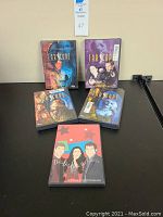 Five Farscape DVD cases displayed on a table, showing cover art for the Premiere DVD, Collection 1, and other season DVDs along with a documentary DVD titled Docu Dot Does the Saturns.