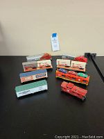 Several vintage HO gauge trains including Santa Fe boxcars, Ralston Purina and Dairymen's League boxcars, a flatcar with three cars, and a red caboose.