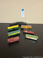 Top-down view of entire train set including black steam locomotive and seven cars in various colors and liveries