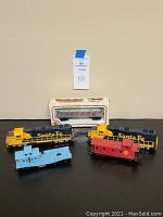 Front view showing 2 yellow Santa Fe locomotives, 1 light blue caboose, 1 red caboose, and boxed train car