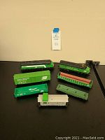 Eight HO scale vintage model train cars arranged on black surface with identification tag behind them.