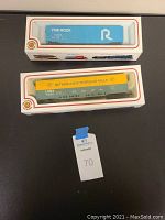 Two boxed HO scale model train cars from Bachmann, one blue and one yellow-green.