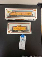 Two boxed Bachmann HO scale model trains, locomotive and caboose, both Union Pacific yellow color.