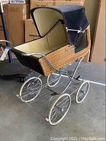 Side view of vintage Gesslein Panorama wicker baby carriage showing wicker body, chrome wheels and handle, and navy canopy.