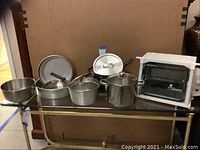 Full view of Showtime Compact Showtime+ rotisserie oven and cookware items including pots, pans, and mixing bowl.