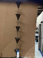 Top section of the copper rain catcher showing the upper cup with petal-like edges and part of the connecting chain.