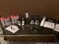 Full lot laid out with sealed headset boxes, handsets, base unit, cords, and manuals visible on a glass surface.