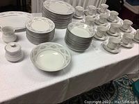 Photo showing the complete set of fine china arranged on a table including plates, cups, saucers, and serving pieces.