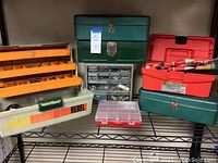 Photo showing multiple fishing tackle and tool boxes with hardware organizers on a metal rack shelf.