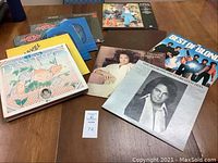 Overview photo showing an assortment of vintage LP records displayed on a wooden surface, with visible covers of Neil Diamond, Carpenters, Abba, and others.