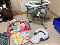 Graco DuoGlider baby swing, colorful baby playmat, and infant sleeping pad together on floor