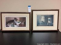 Both framed prints displayed side by side on a black surface against a plain background.