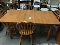Full view of wooden dining table fully extended with four matching chairs around it, showing the overall set condition and style.