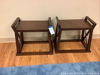 Two matching dark wood Pier 1 end tables positioned side by side against a wall, showing entire pieces with surfaces and handle style sides visible.