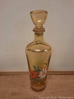 Amber glass decanter with stopper and hand-painted floral design in red, white, and green colors