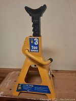 Side view of the yellow 3 ton jack stand showing the support saddle and sturdy triangular base.