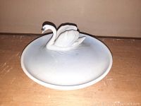 Top view of white porcelain plate with sculpted swan figure at center for jewelry holding.