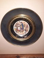 Full view of the framed bone china plate showing the Regency couple scene and brass outer frame with black and gold accents
