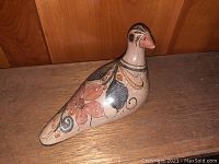 Side view of pottery bird showing floral painted design on body and beak