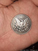 Reverse side of 1879 O Morgan Silver Dollar coin showing eagle with wings spread, mint mark 'O', inscriptions 'UNITED STATES OF AMERICA', 'IN GOD WE TRUST', and 'ONE DOLLAR'. Coin is held in hand for scale.