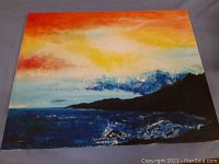 Photo of a colorful landscape painting showing a sunset sky over a dark mountain range and reflective water.