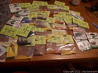 Fishing tackle and lures laid out on a wooden table showing many Bucktail Jig packages and other fishing lures.