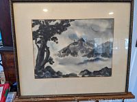 Framed watercolor mountain landscape painting with visible signature monogram on front.