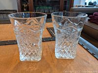 Pair of clear square-based tumblers with raised pineapple and floral decorative glass patterns taken from the front to show detail and condition.