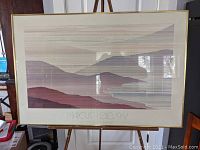 Full view of the framed poster showing stylized landscape and signature.