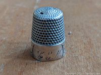 Front angle showing the pierced dimple pattern on the thimble top and the inscribed initials or marking on the lower band.