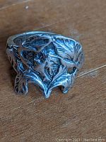 Front view of sterling silver ring showing raised woman face design with floral and leaf motifs in Art Nouveau style