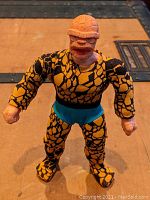 Front view of The Thing action figure in original patterned fabric outfit with blue shorts.