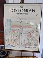 Full view of framed illustrated vintage poster 'The Bostonian View of the World' on an easel, showing the overall condition and framing.