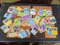 Pile of assorted Pokémon trading cards showing variety of characters and energy cards on table.