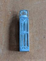 Full frontal photo of the Art Deco sterling silver overlay glass perfume bottle showing the geometric cage design and clear glass vial inside.