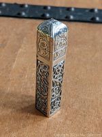 Front view of the sterling silver overlay perfume vial showing pierced and chased floral patterns