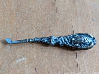 Close-up of the Art Nouveau style sterling silver handle cuticle trimmer with floral details and trimming blade.